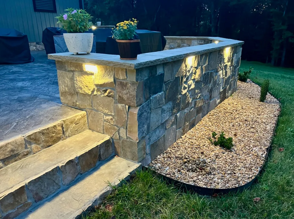 Outdoor stone wall feature with built-in accent lighting and landscaping