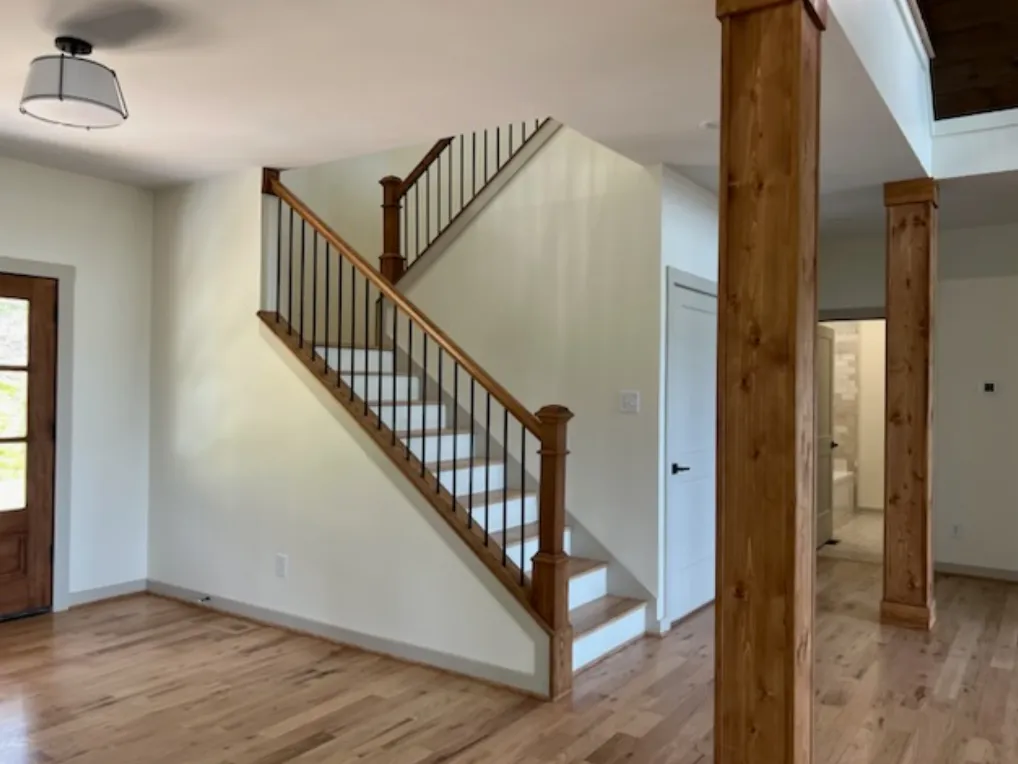 Traditional wood staircase with black spindles and exposed beams