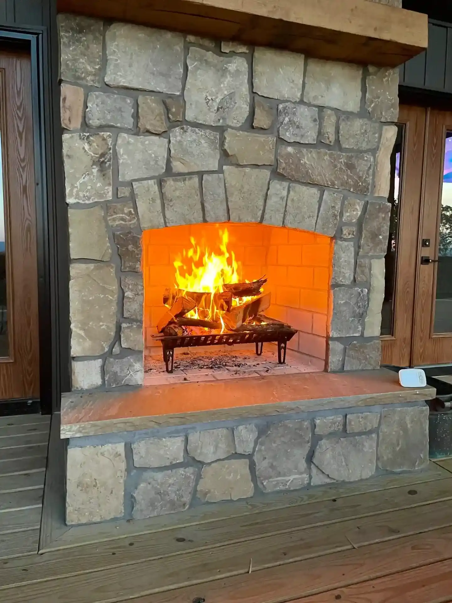 Outdoor stone fireplace with active fire and rustic design