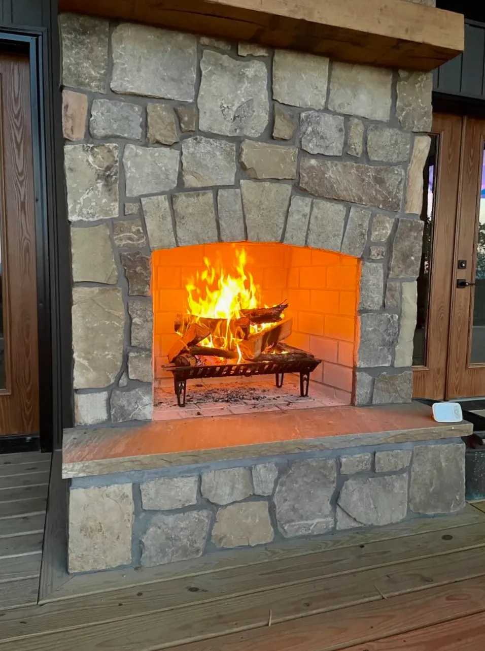 Outdoor stone fireplace with live flames and rustic setting