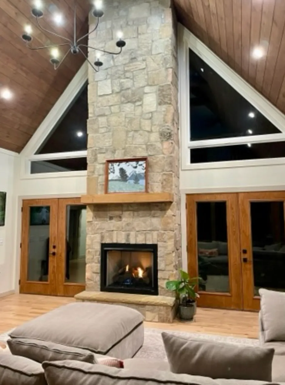 Modern stone fireplace with vaulted ceiling and large windows