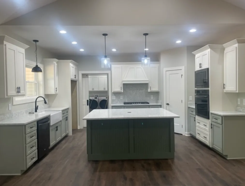 Large kitchen with white cabinets and green island
