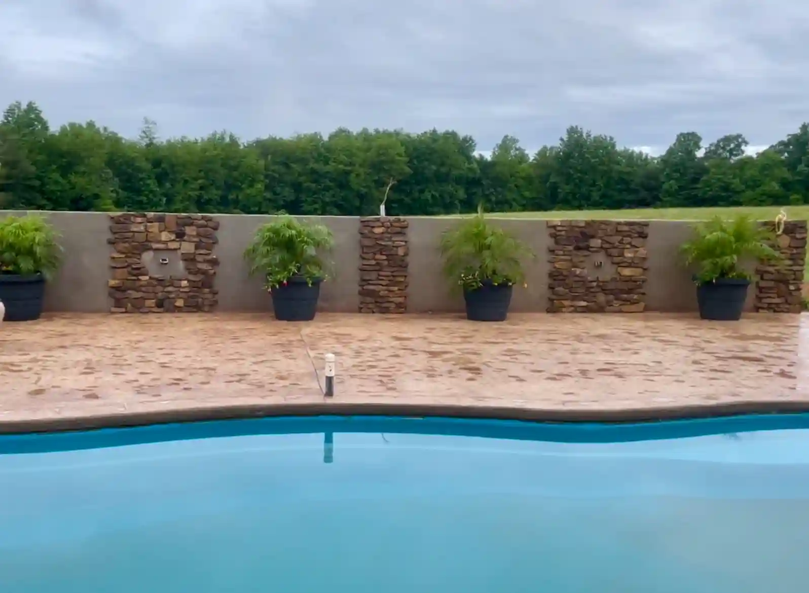 Pool area with decorative stone wall features and professional landscaping