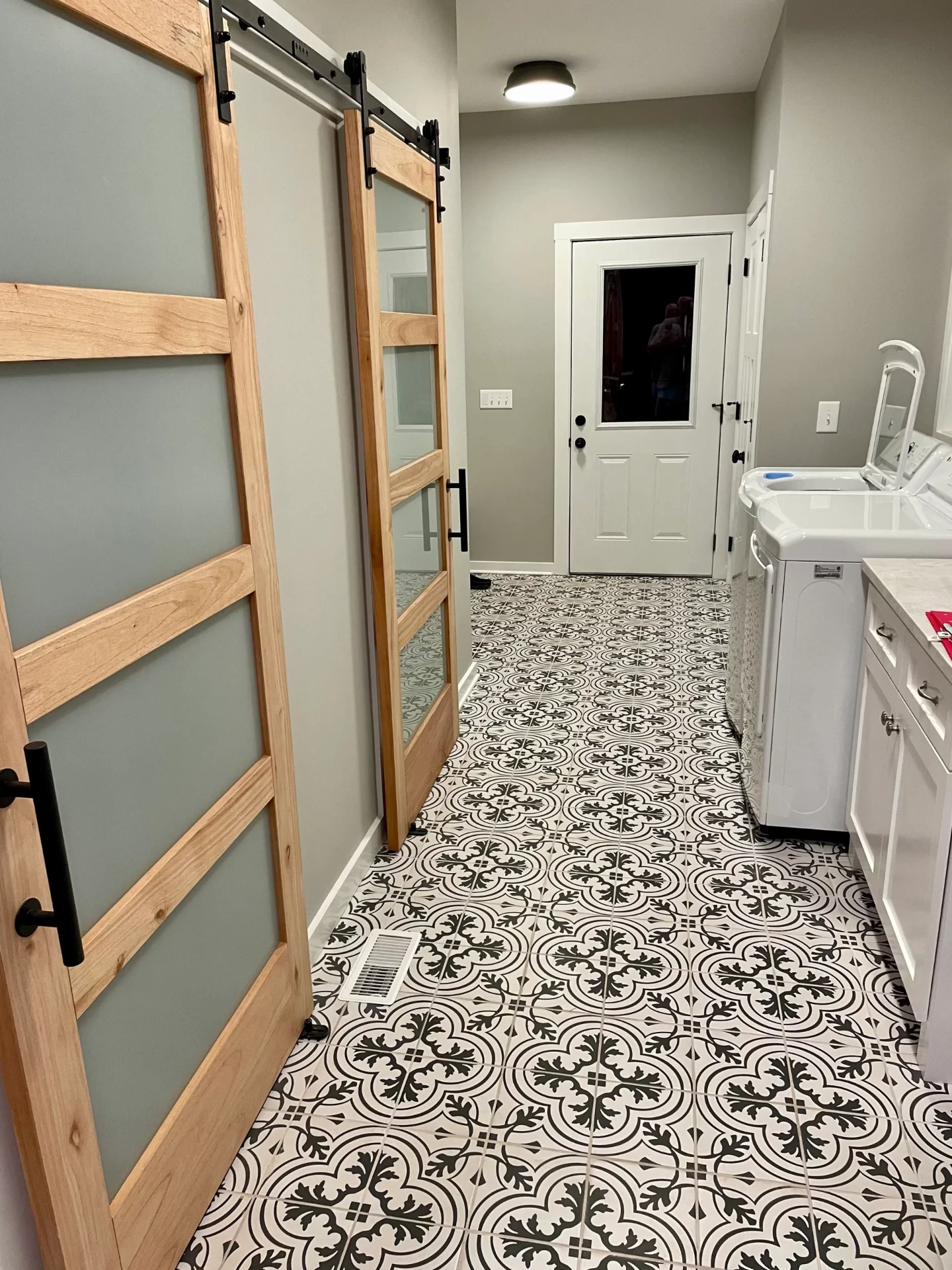Glass panel barn doors in mudroom with patterned tile flooring
