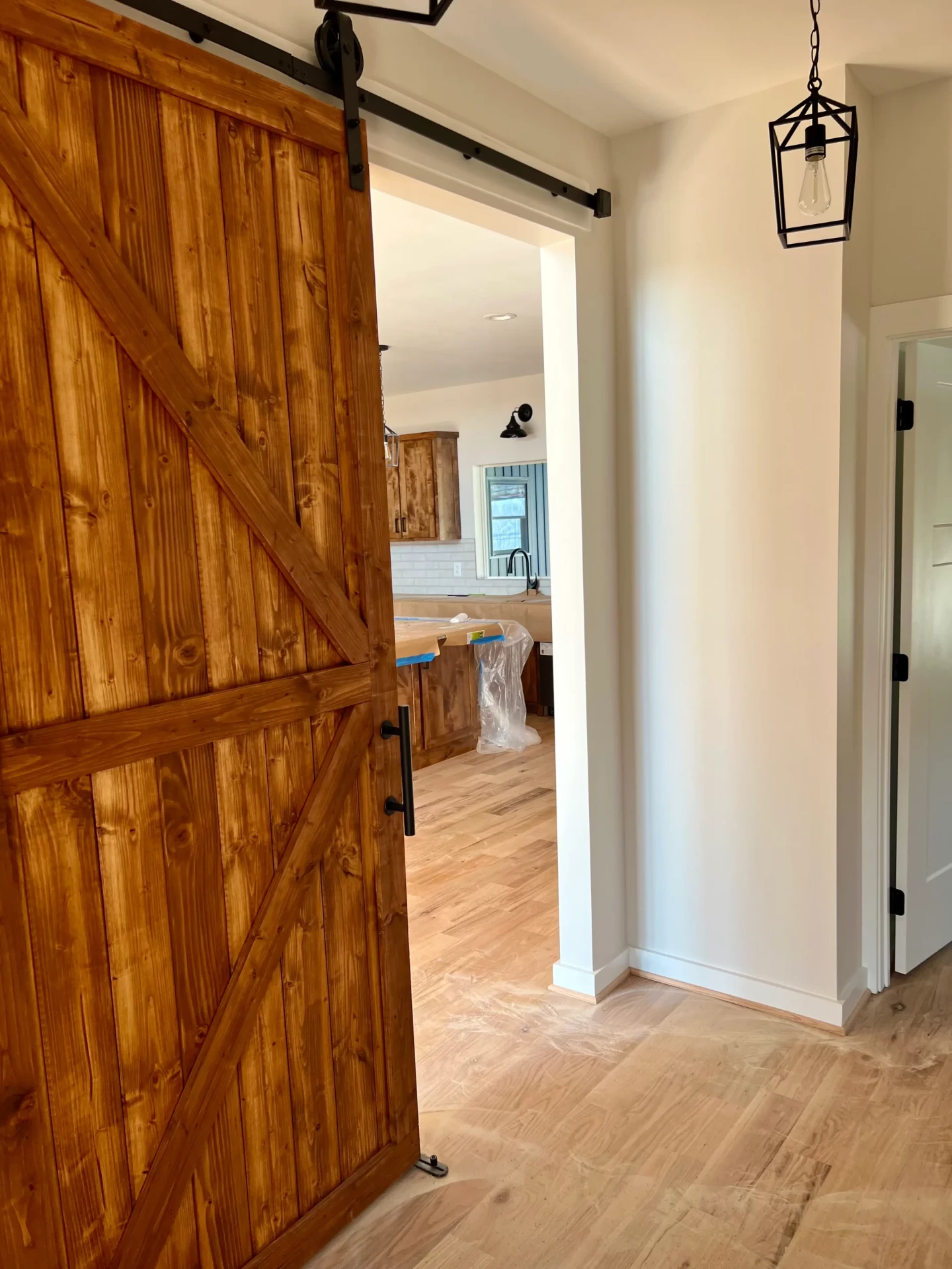 Large sliding barn door opening to kitchen with natural wood finish