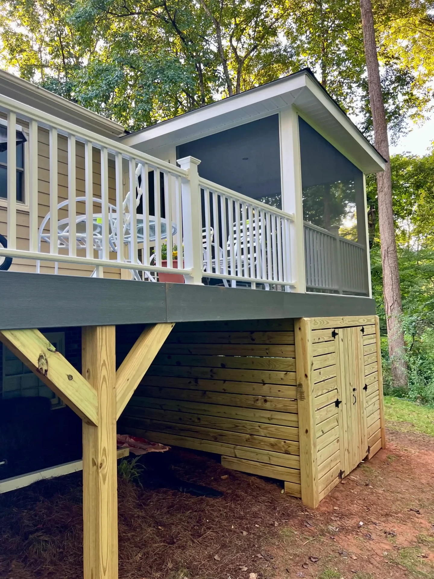 Elevated deck with white railings and wood storage enclosure underneath