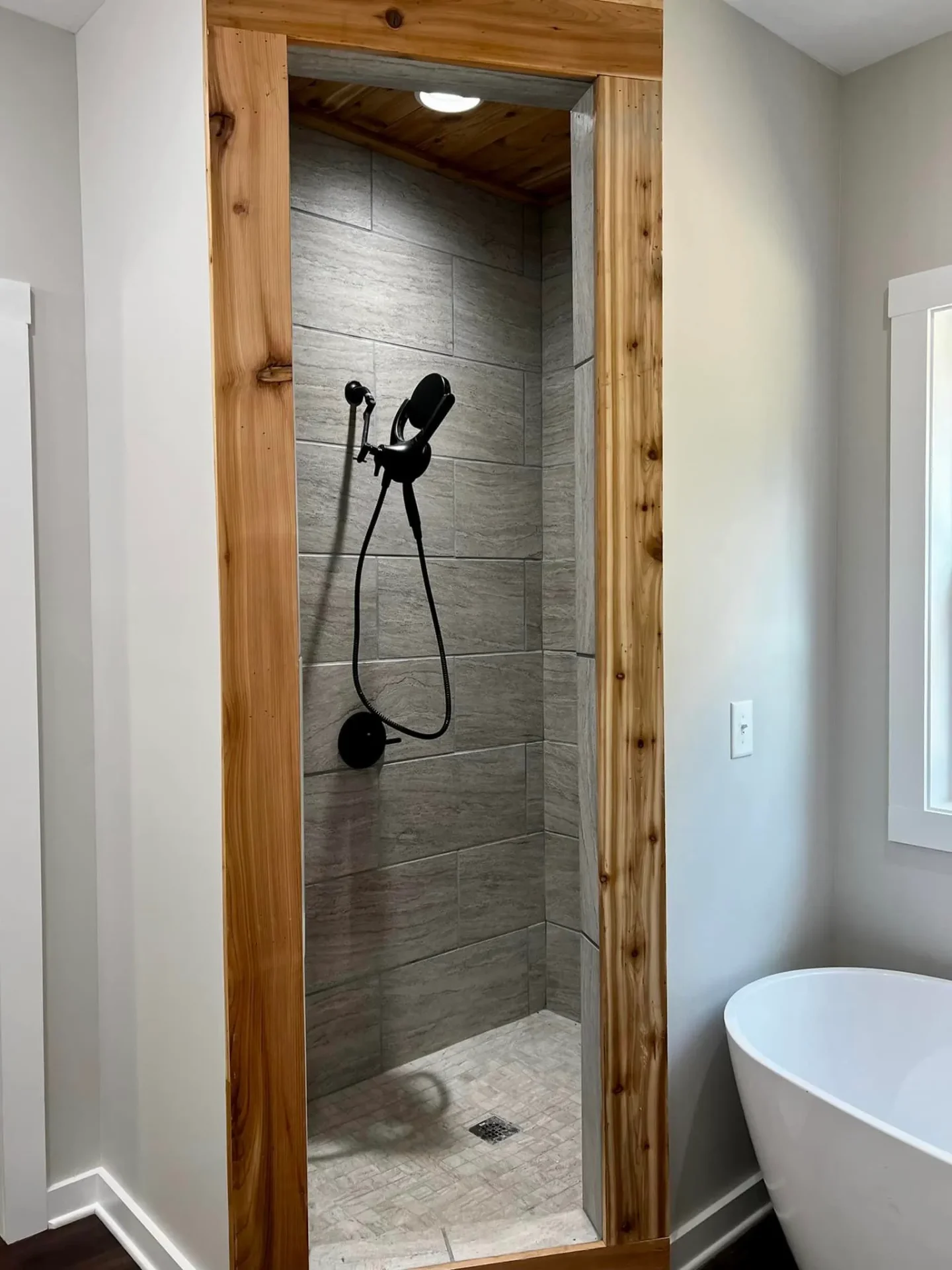 Open shower with wood beam frame and stone tile