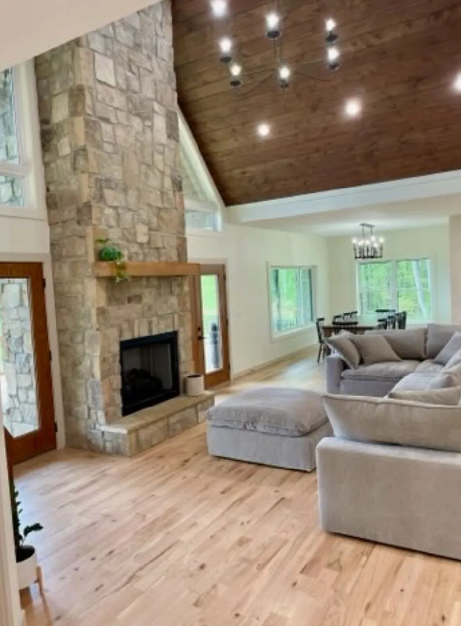 Two-story stone fireplace with wood ceiling and modern furnishings