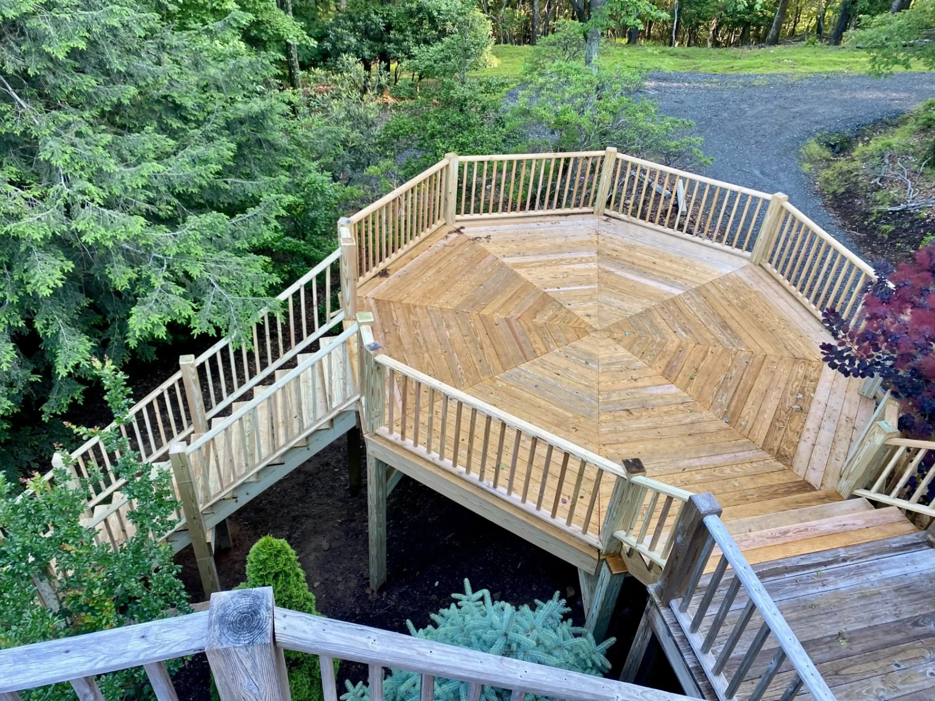 Beautiful octagonal wooden deck with railings surrounded by natural landscaping