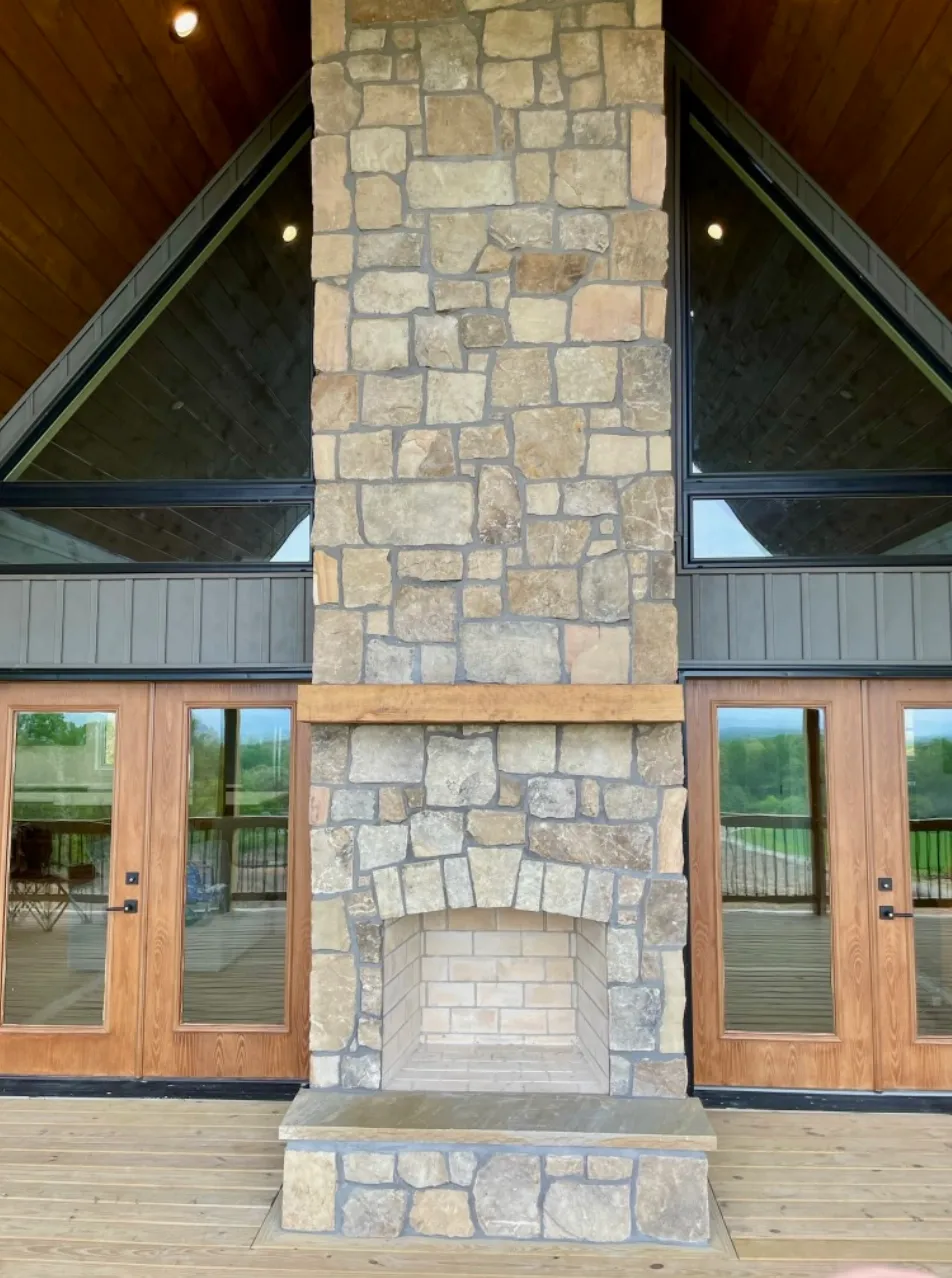 Covered outdoor living space with stone fireplace and French doors