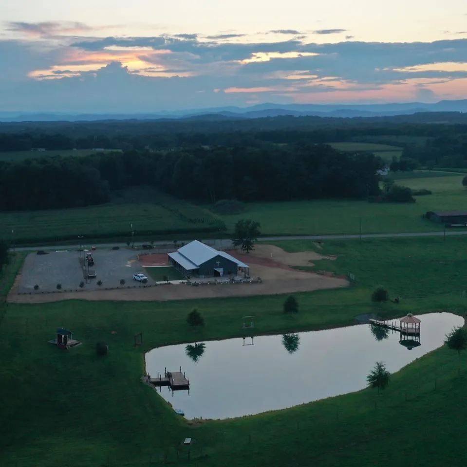 Aerial view showing the barn, pond, and mountain landscape