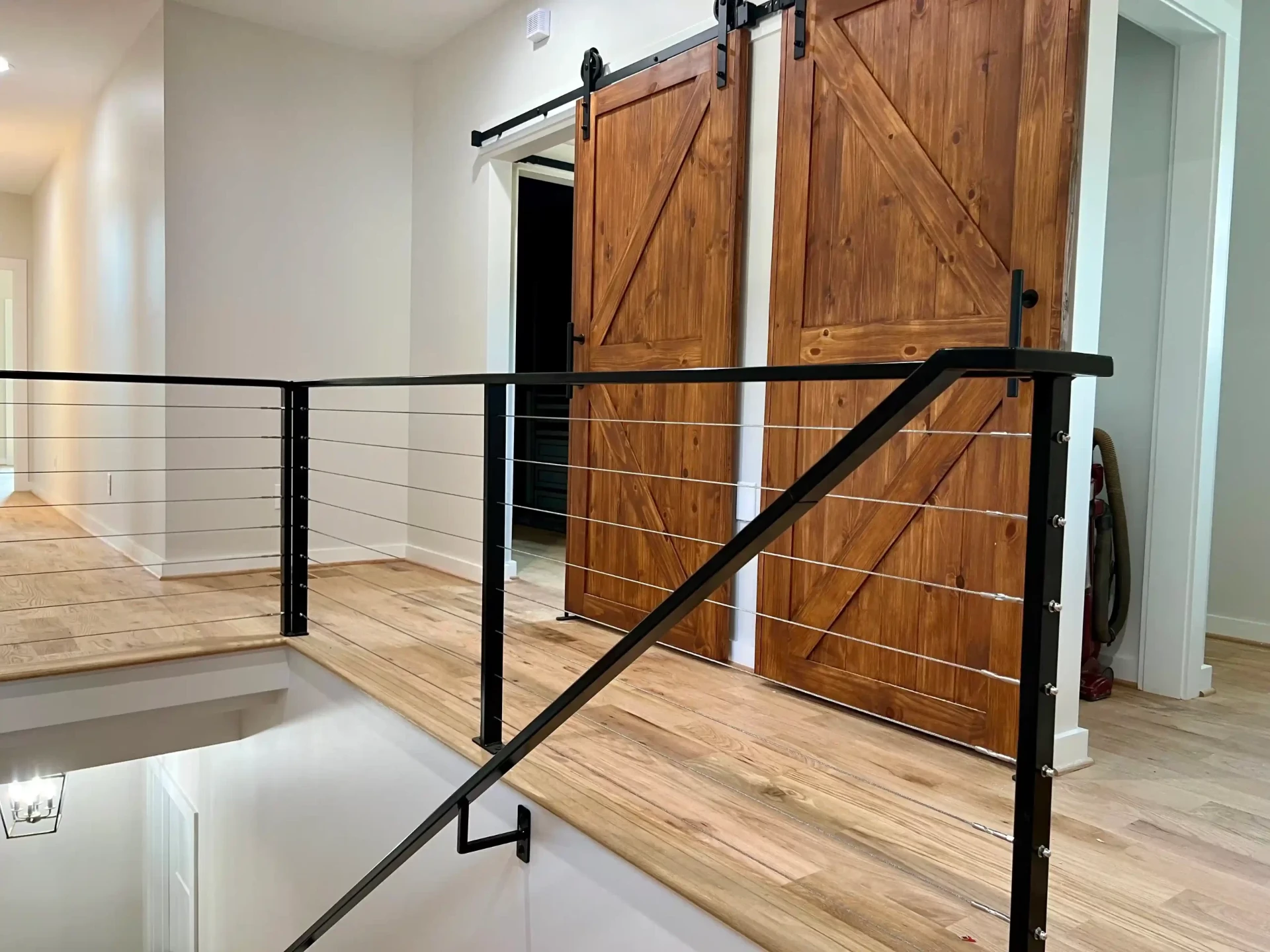 Interior staircase with barn doors and modern cable railing