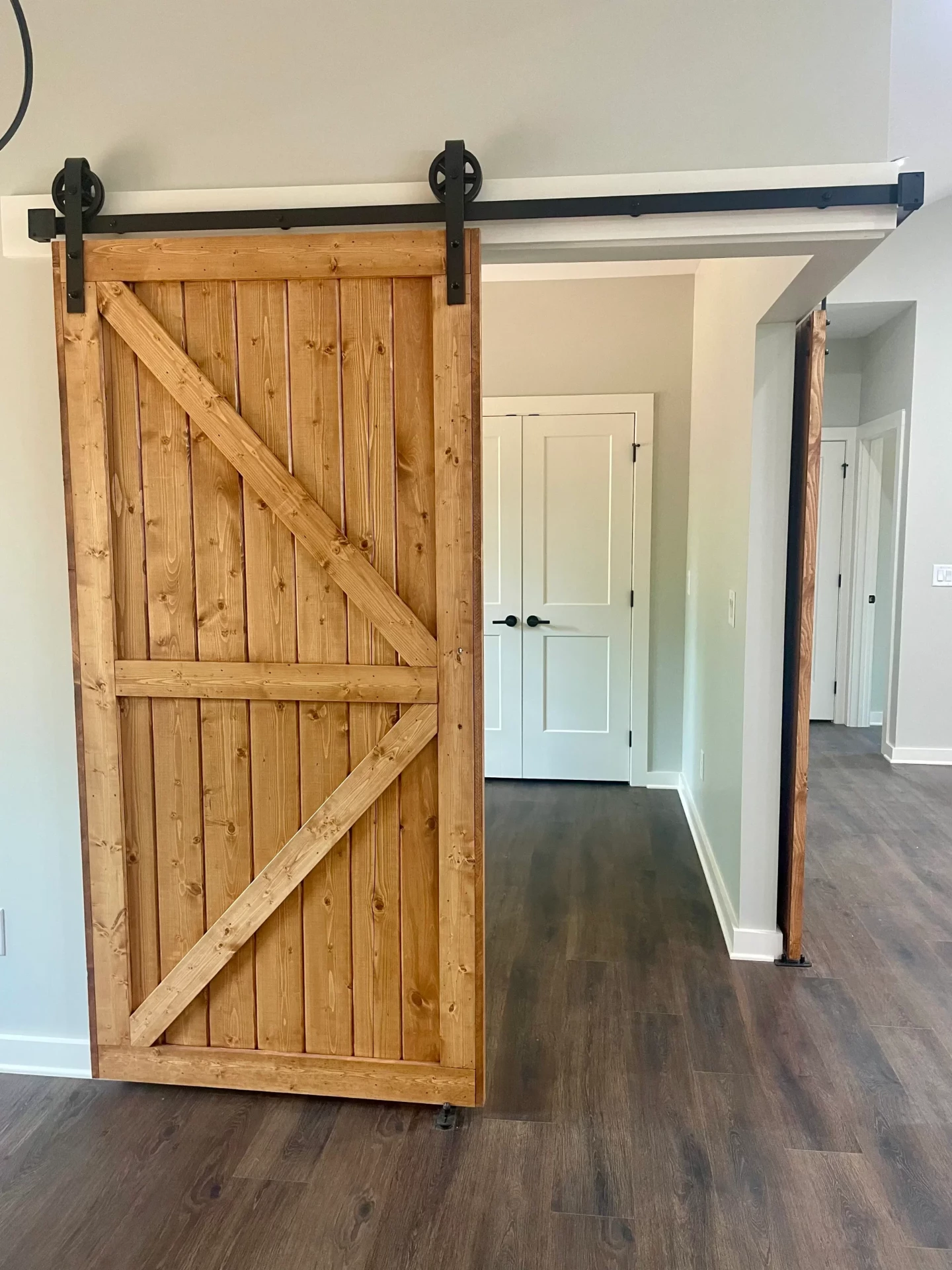 Natural wood barn door with black hardware in hallway