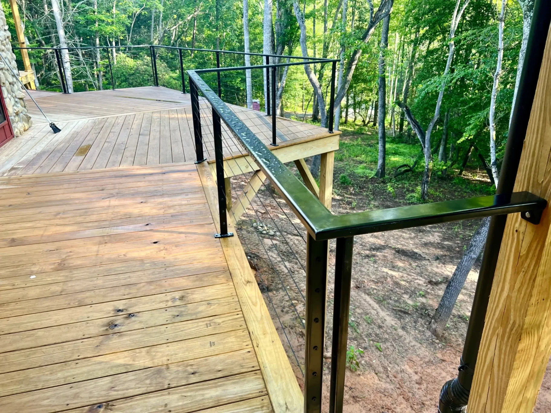 Outdoor deck staircase with black metal railing and natural setting
