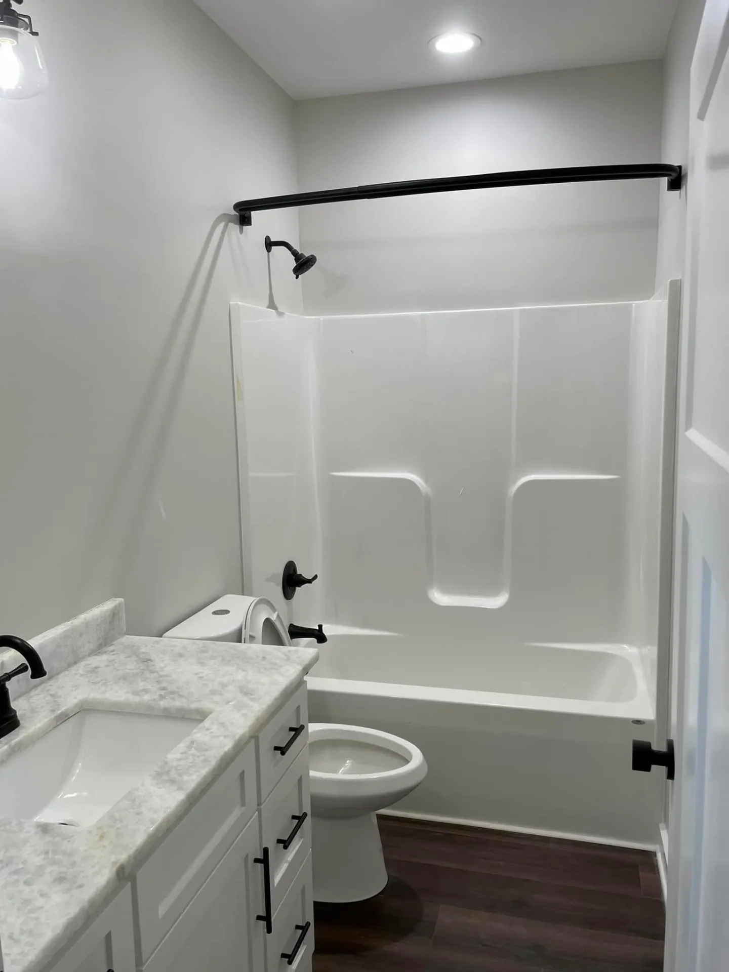 White bathroom with tub/shower combo and marble countertops